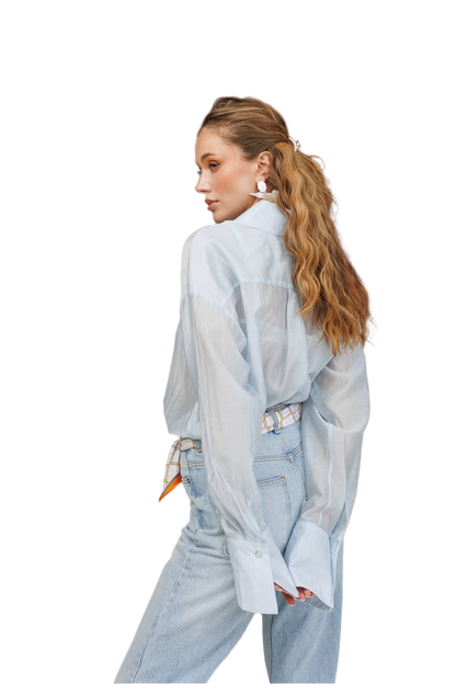 Woman wearing a light blue oversized shirt and jeans on a white background