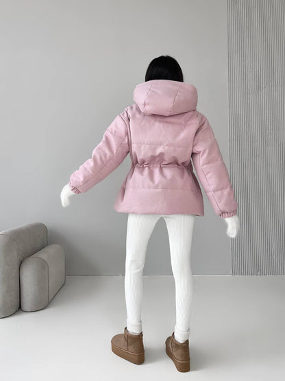 Person wearing a pink puffer jacket in a minimalistic room.