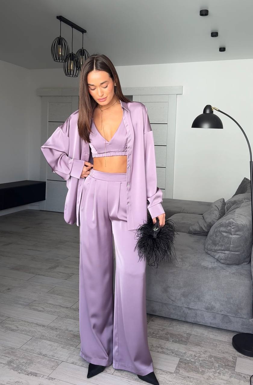 Woman in a lavender outfit standing in a modern living room.