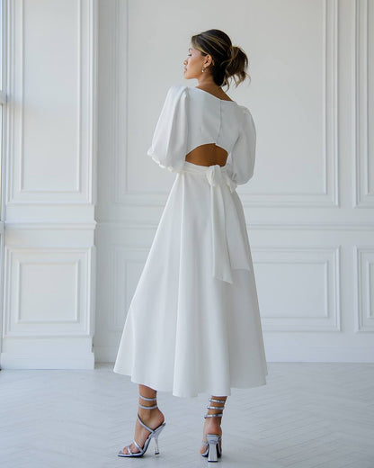 Woman wearing a white dress with a cut-out back in a minimalistic setting