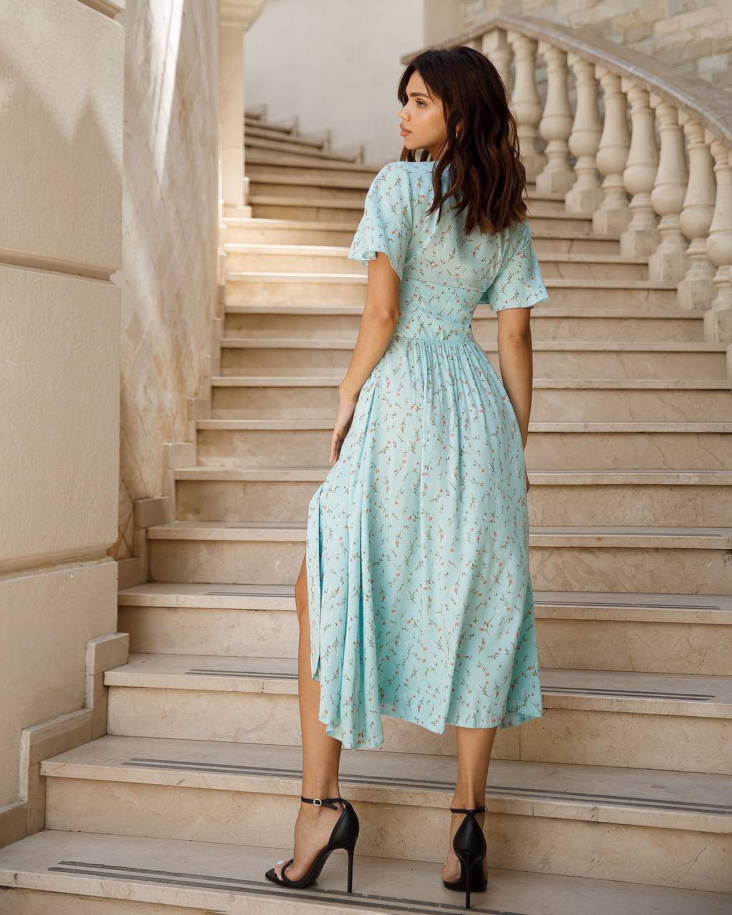 Woman in a light blue dress standing on a staircase