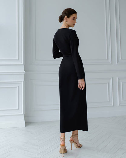 Woman wearing a black dress in a minimalistic room with white walls and floor.