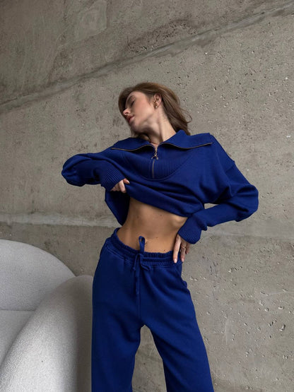 Person wearing a blue outfit standing against a concrete wall.