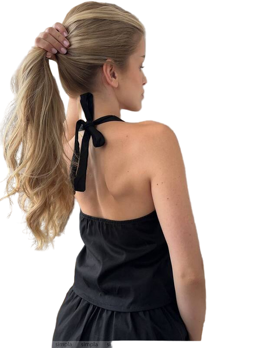 Woman with a high ponytail wearing a black halter top against a white background