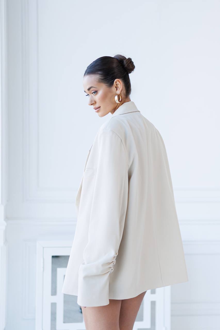 Woman wearing a beige blazer and shorts in a minimalistic setting
