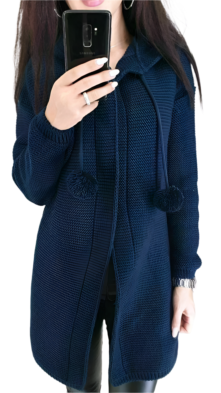 Person wearing a blue knitted cardigan with pom-pom details, holding a phone.