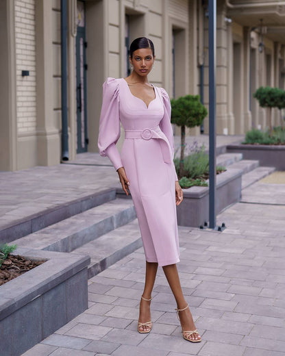 Woman in a pink dress standing on a city street.