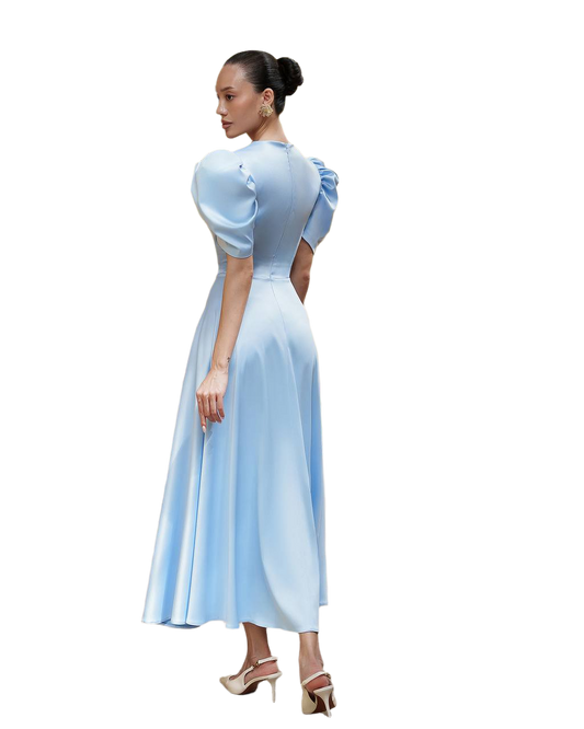 Woman wearing a light blue dress with puffed sleeves on a white background