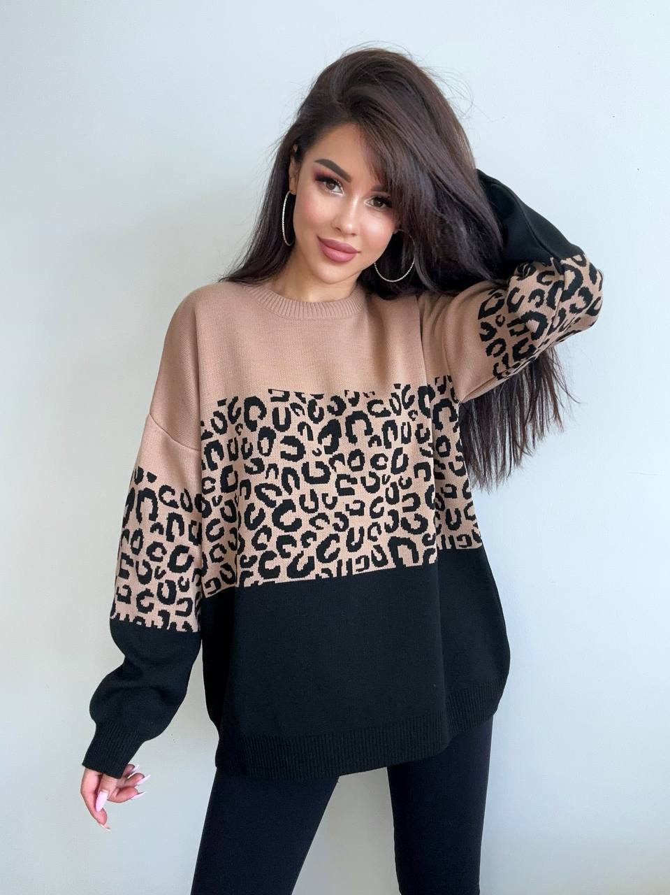 Woman wearing a sweater with a leopard print pattern against a white background