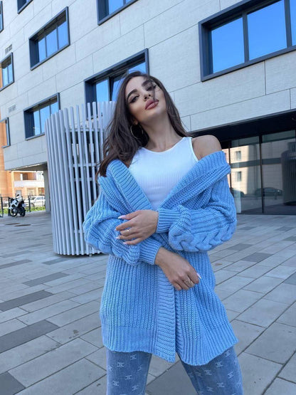 Woman wearing a blue knitted cardigan and white top in an urban setting