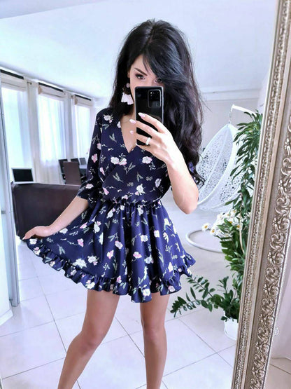 Woman taking a mirror selfie wearing a navy floral dress.