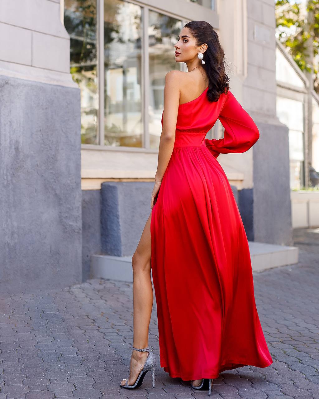 Woman in a red one-shoulder dress standing outdoors.
