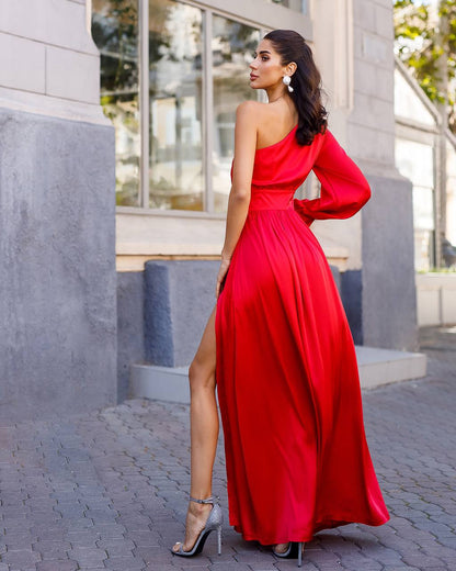 Woman in a red one-shoulder dress standing outdoors.