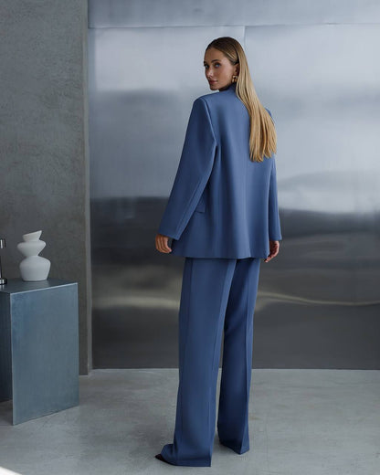 Woman in a blue suit standing in a modern interior setting.