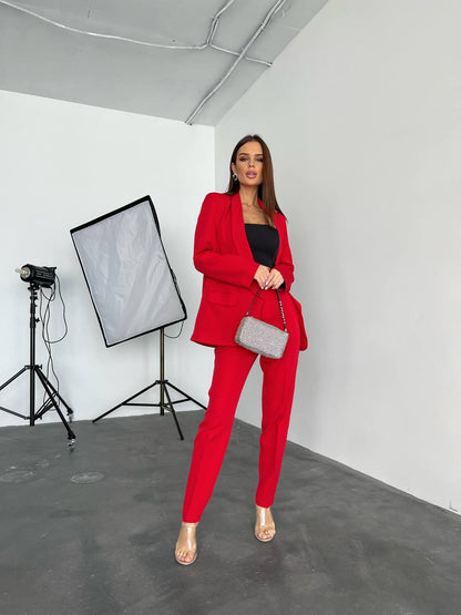 Woman in a red suit standing in a studio setting with photography equipment.