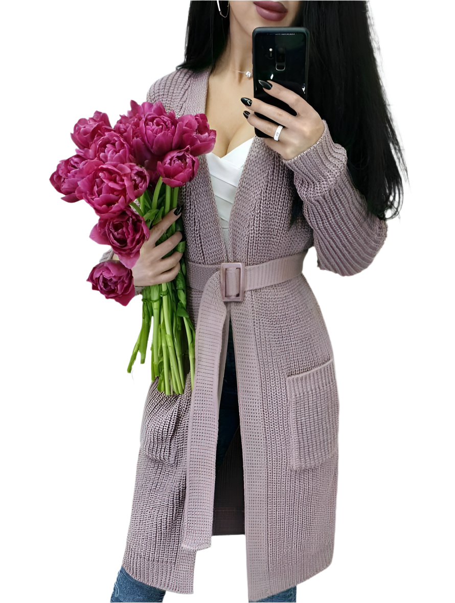Person wearing a long knitted cardigan holding pink flowers on a white background