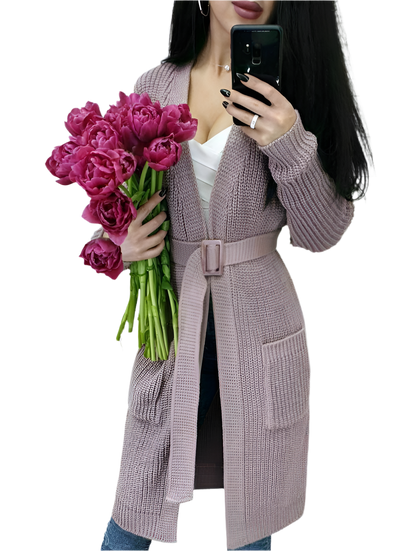 Person wearing a long knitted cardigan holding pink flowers on a white background