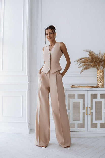 Woman in a beige outfit standing in a stylish interior setting.