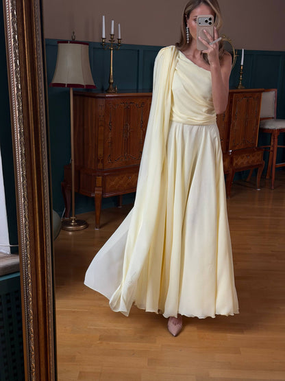 Woman in a long, light-colored dress taking a mirror selfie in an elegant room.