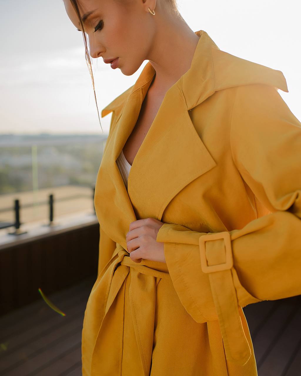 Woman wearing a yellow trench coat with a blurred background