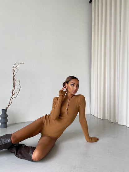Woman in a brown dress sitting on the floor with a minimalistic background
