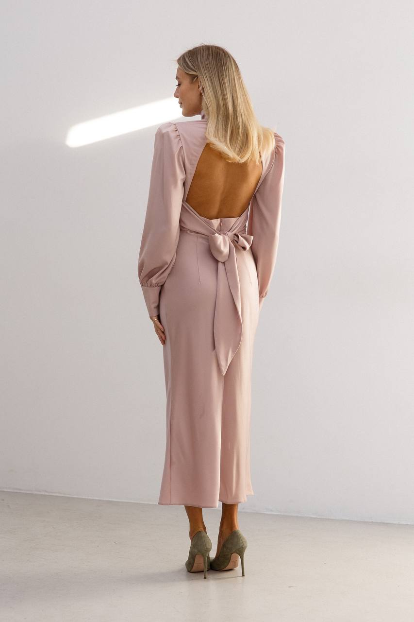 Woman wearing a pink dress with an open back in a minimalistic setting