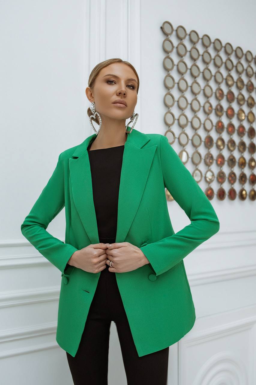 Woman wearing a green blazer in an indoor setting with decorative elements.