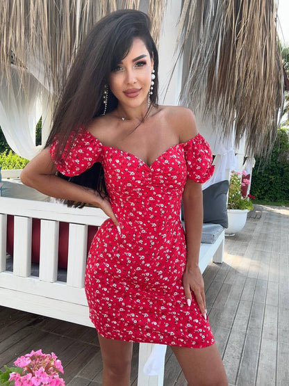 Woman wearing a red floral dress standing outdoors.