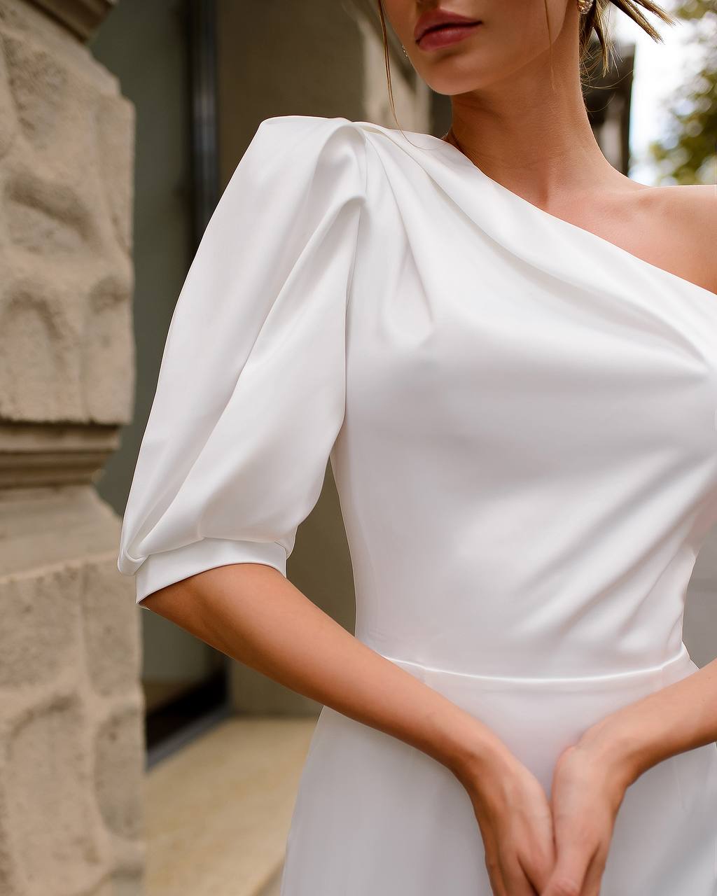 White one-shoulder dress with puff sleeves worn by a model.