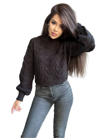 Woman wearing a dark gray cable knit sweater and light blue jeans on a white background