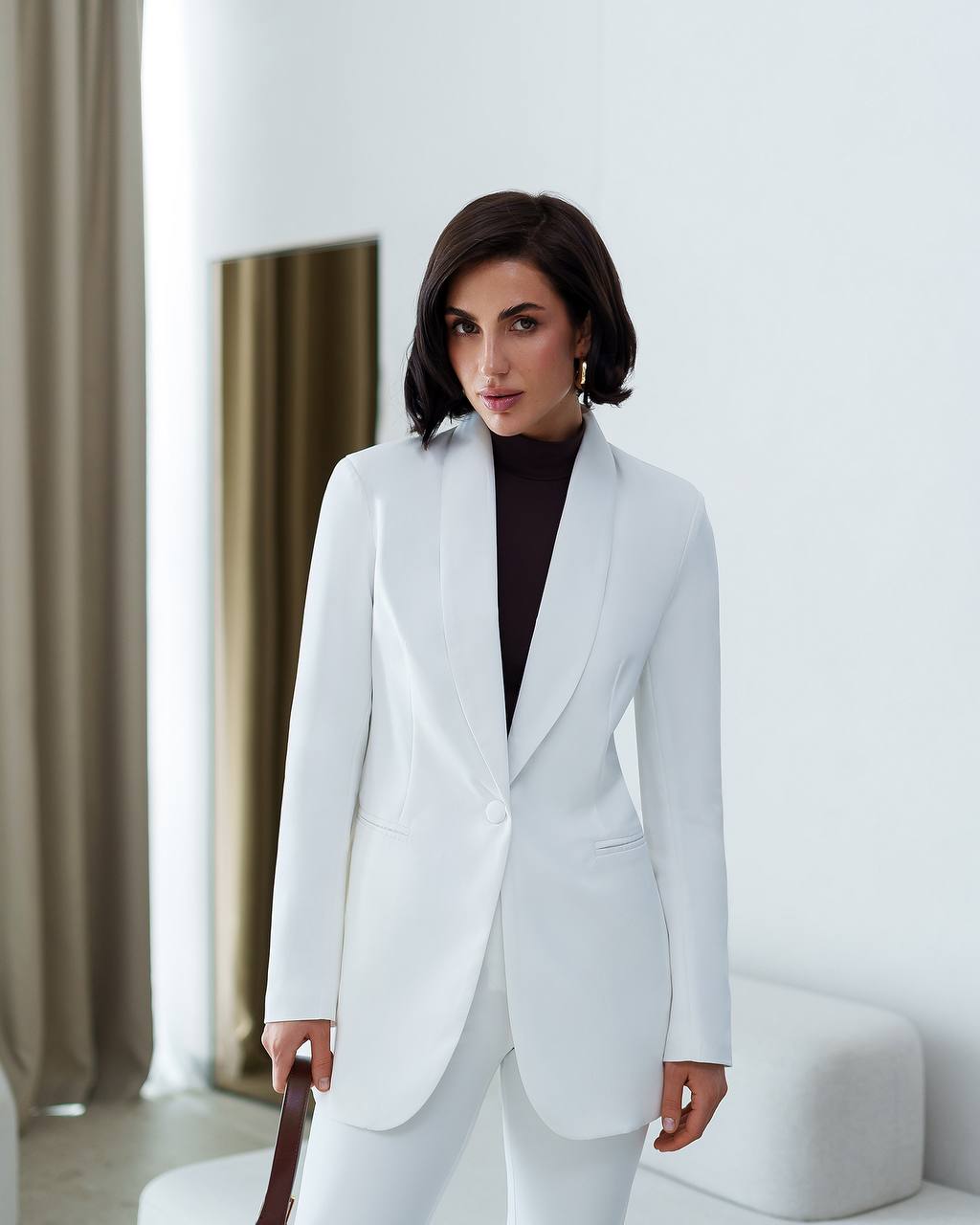 Woman wearing a white suit in a minimalistic room