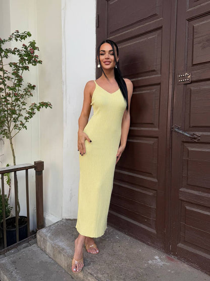 Woman in a yellow dress standing in front of a brown door.