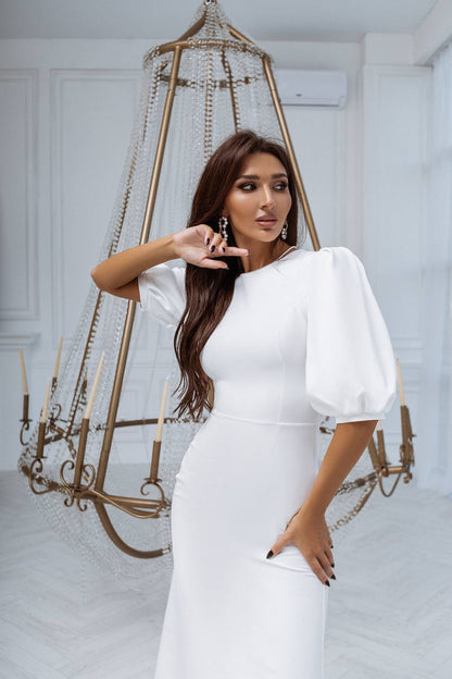 Woman in a white dress posing in a room with decorative elements
