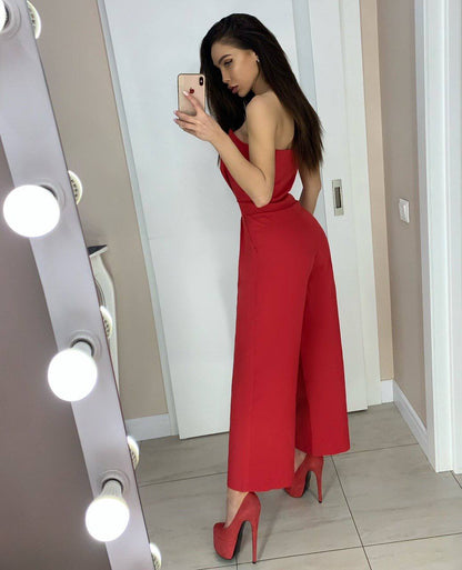 Woman in a red jumpsuit taking a mirror selfie in a well-lit room.