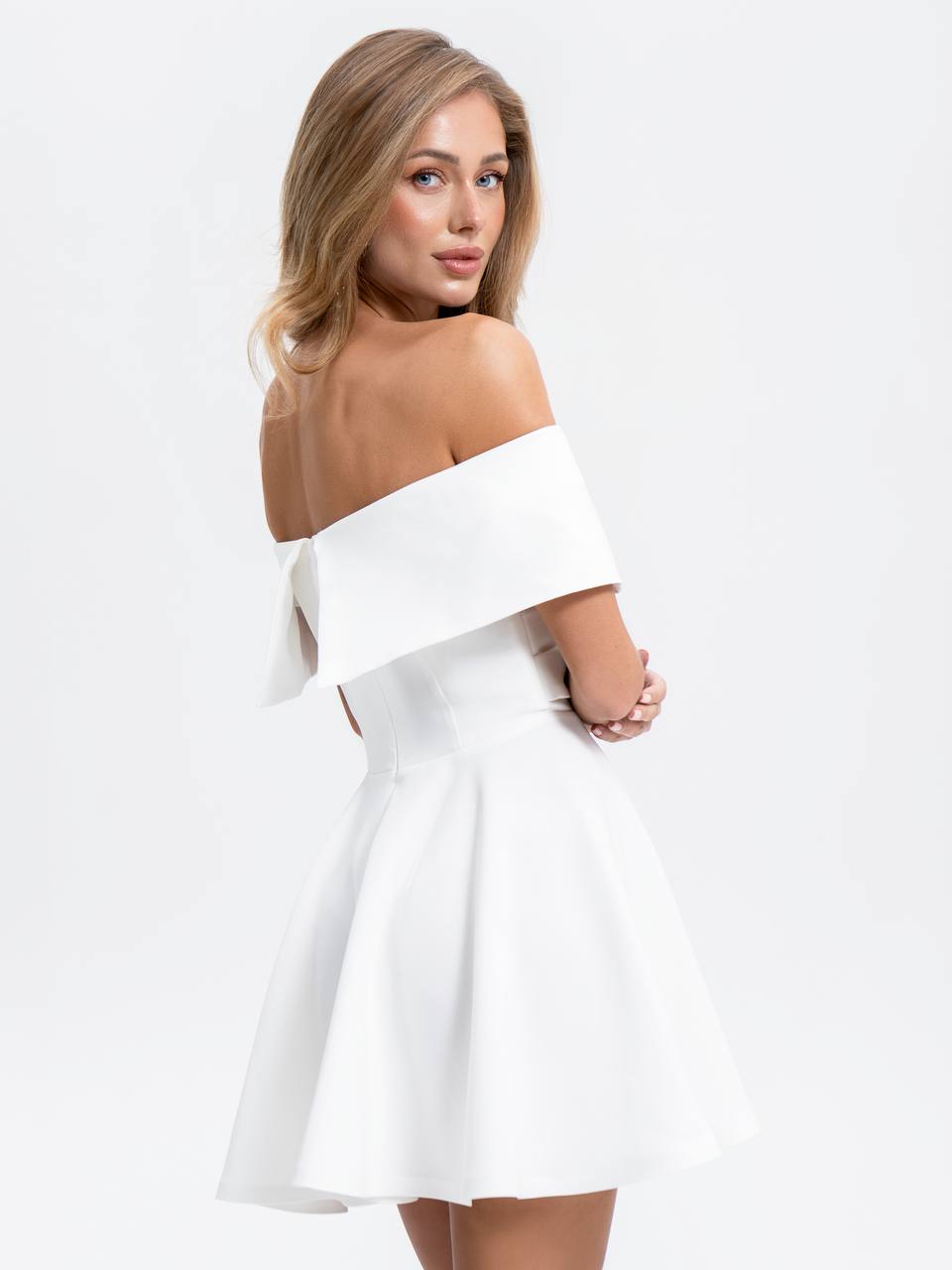 Woman wearing a white off-shoulder dress on a light gray background