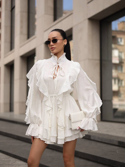 Woman wearing a white ruffled dress standing on a city street.
