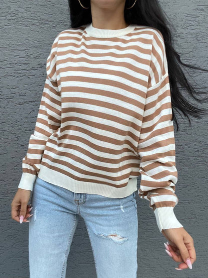Person wearing a brown and white striped sweater with light blue jeans against a gray background