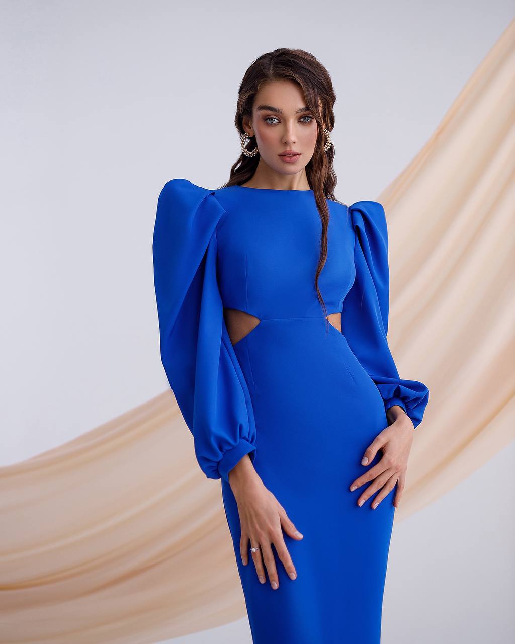 Woman wearing a blue dress with puffed sleeves against a beige and white background