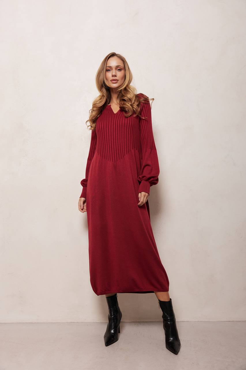 Woman wearing a red dress with long sleeves against a plain background