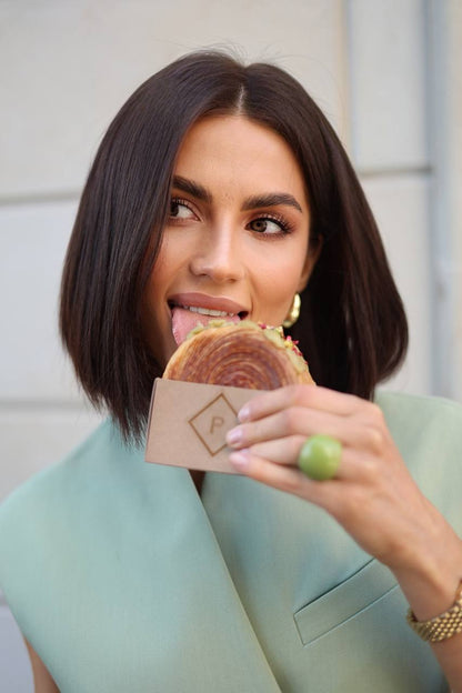 Woman holding a sandwich with a branded paper bag outdoors