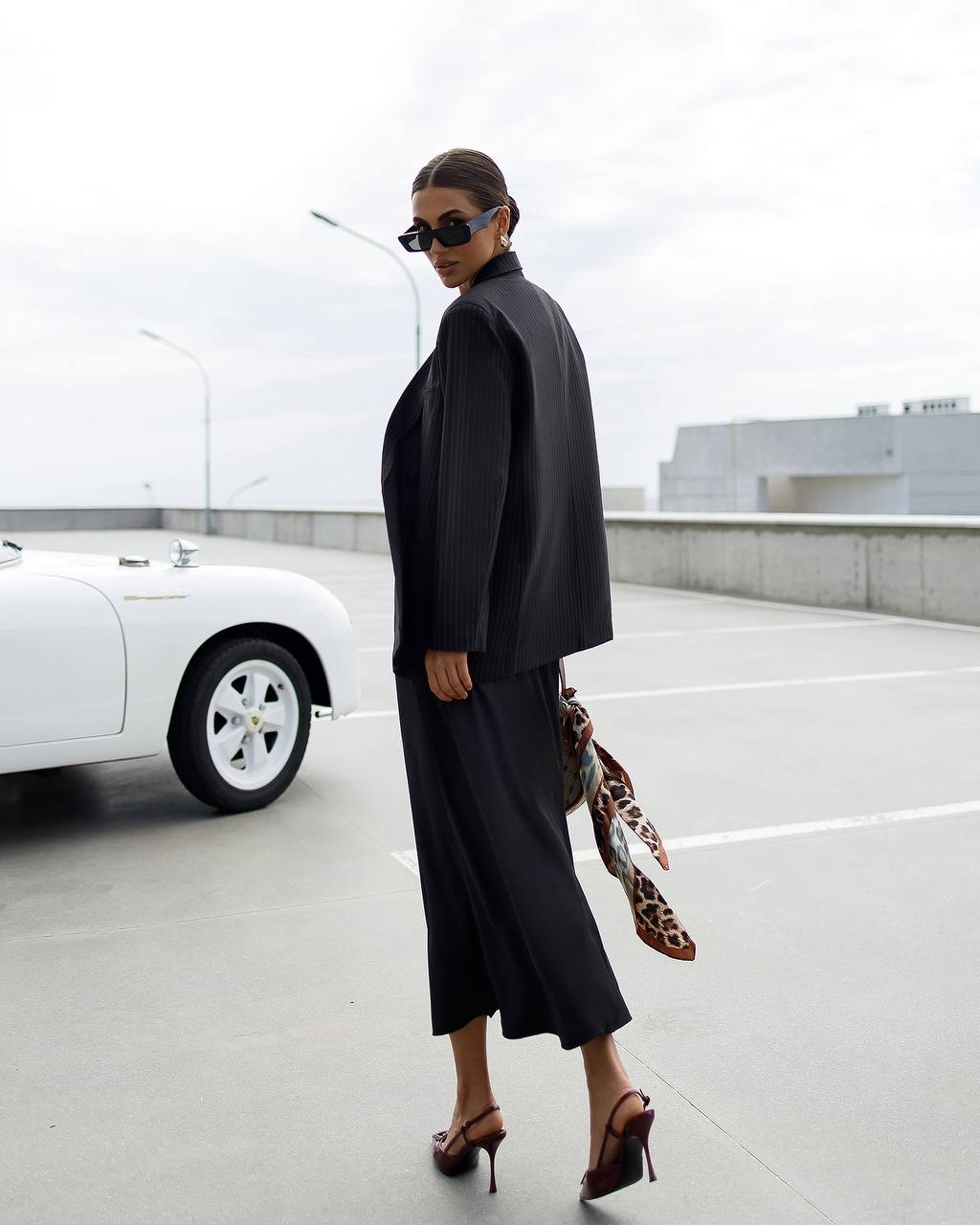Woman in a black outfit with a leopard print bag in an urban setting