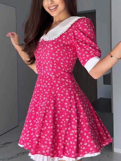 Woman wearing a pink floral dress with white accents in an indoor setting