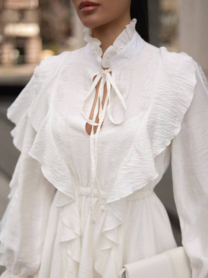 White blouse with ruffled details worn by a person, blurred background