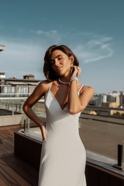 Woman in a white dress on a rooftop with cityscape background