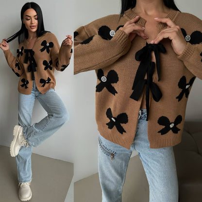 Woman wearing a brown sweater with black bow designs, standing against a plain background.