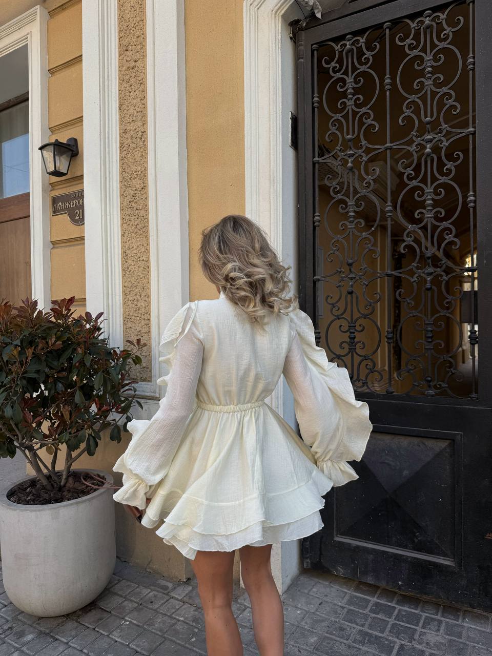 Woman in a white dress standing in front of a decorative door.