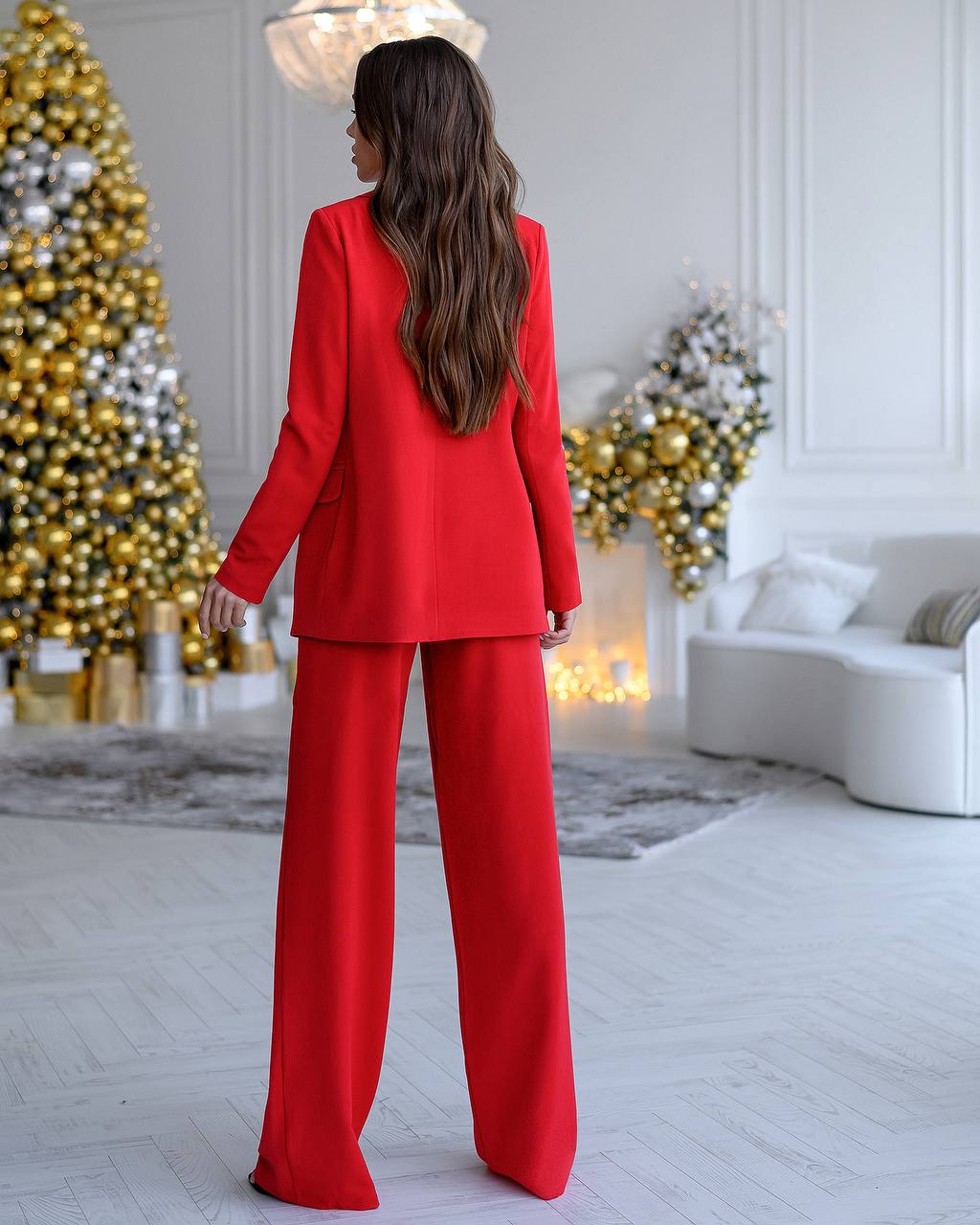 Person wearing a red suit in a decorated room with Christmas trees.