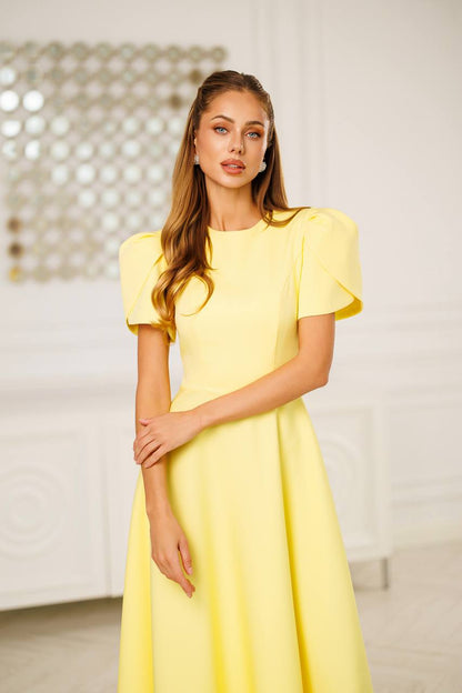 Woman wearing a yellow dress with ruffled sleeves in an indoor setting