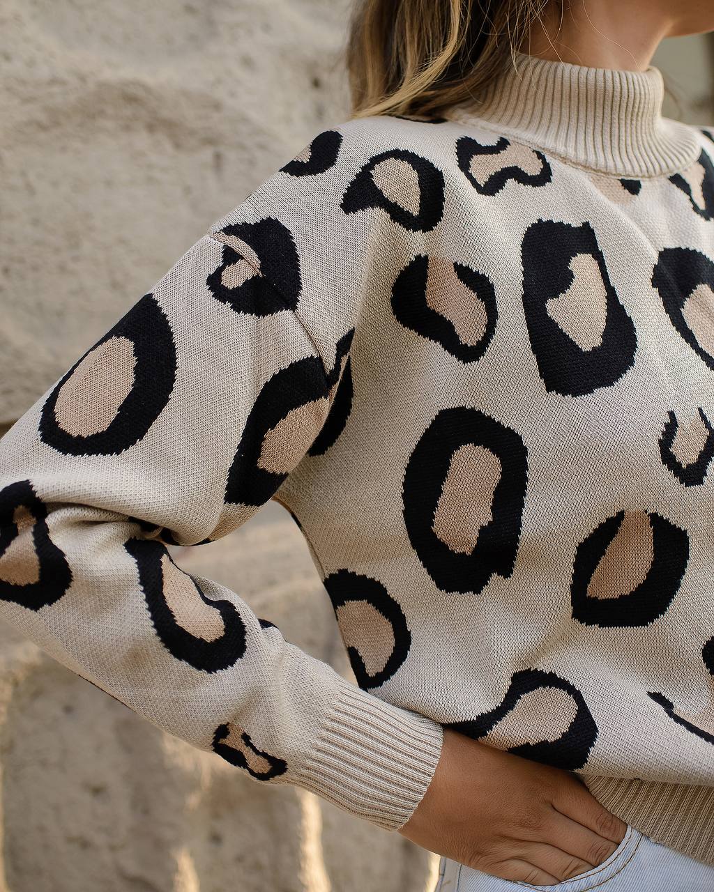 White sweater with black leopard print pattern worn by a person.