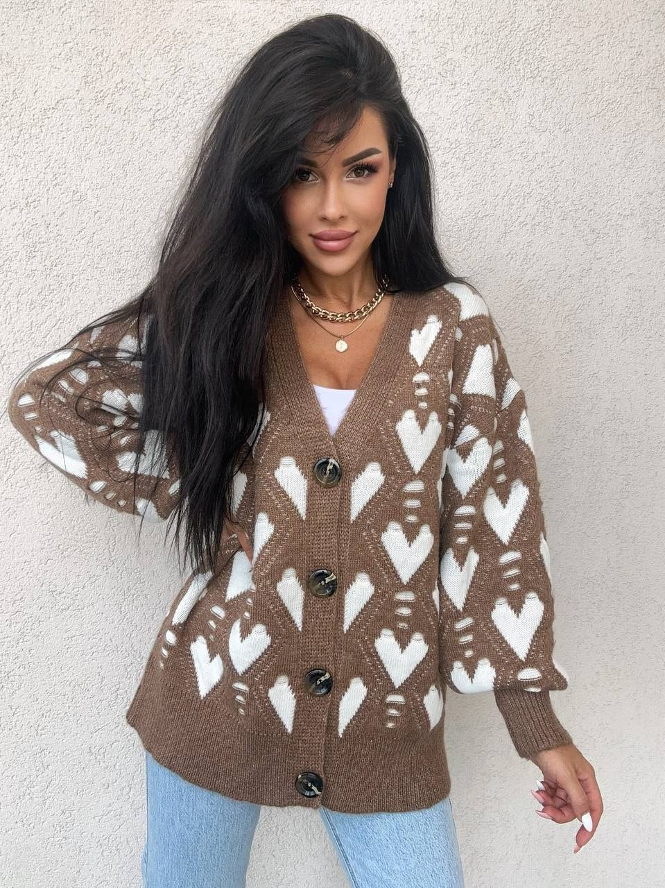Woman wearing a brown cardigan with white heart patterns against a light background